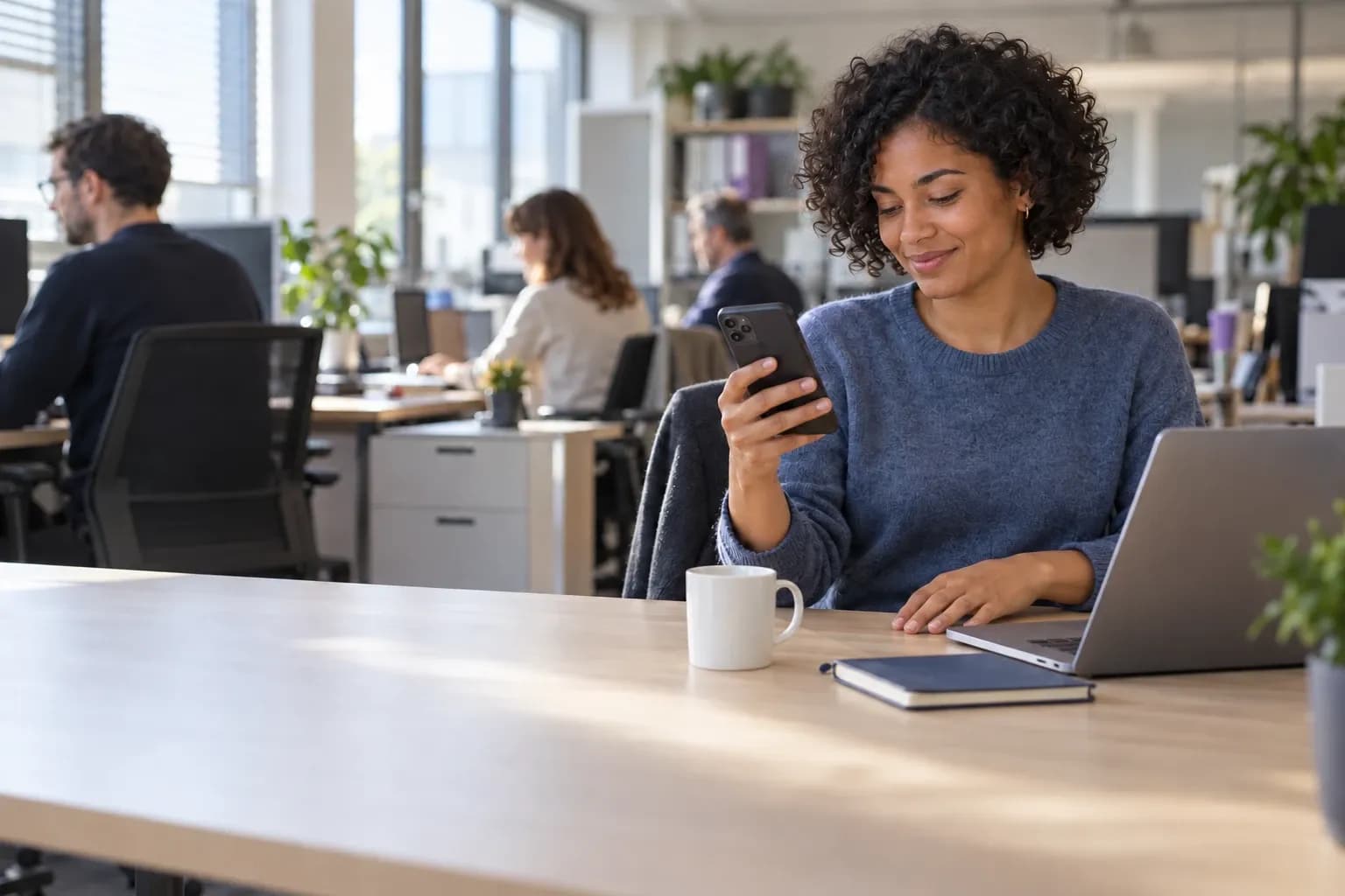 Une collaboratrice répond sur son téléphone, assise à son poste dans un open space